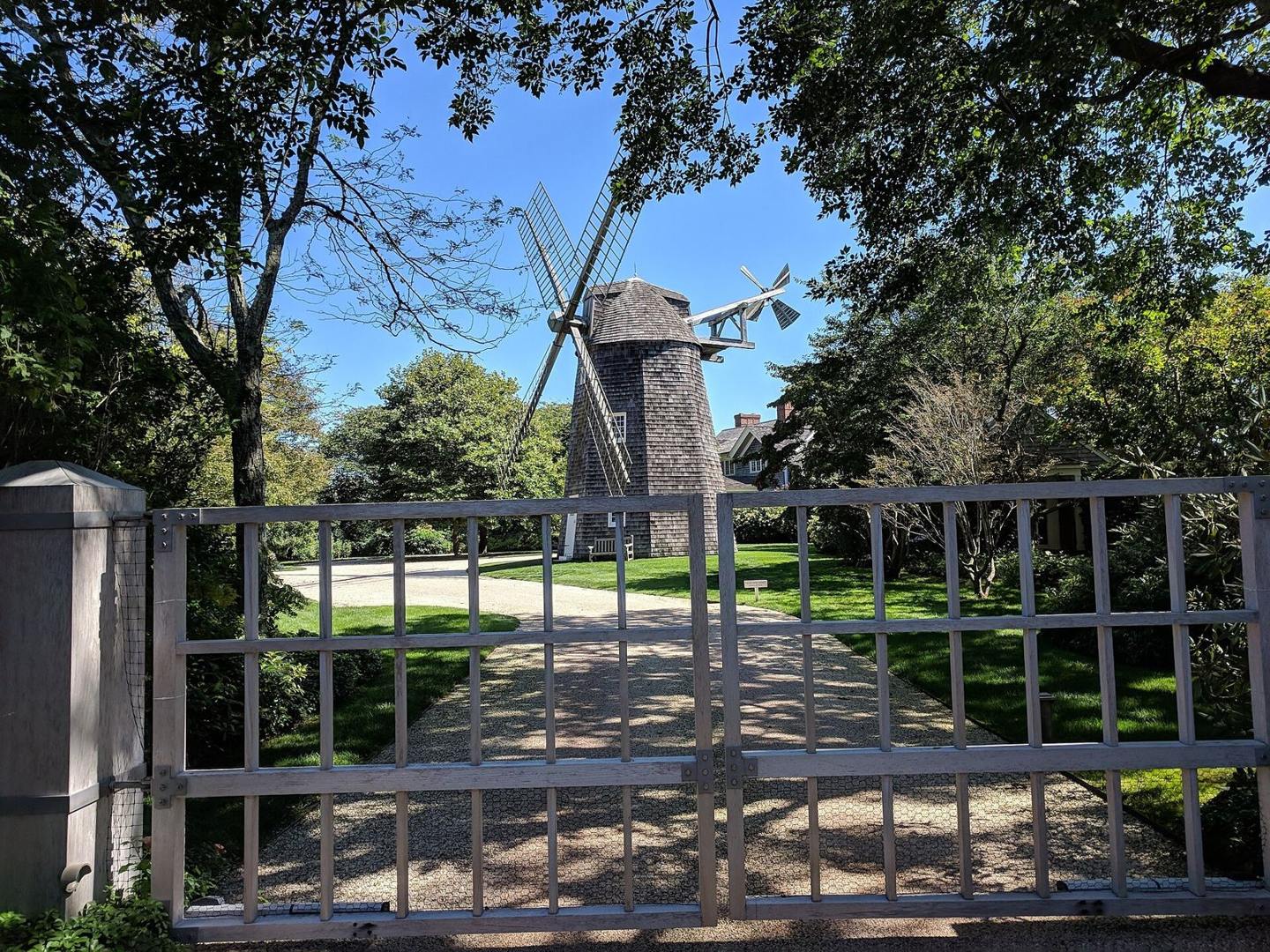Hayground Windmill beyond a gate and mature trees