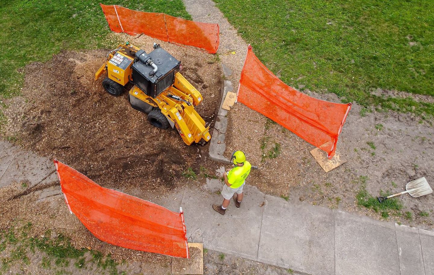 Overhead view of a stump grinder working inside a safety barrier